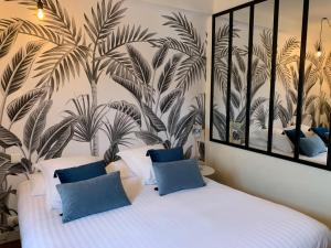 a bedroom with a white bed with blue pillows at Logis Hôtel Le Central in Coulon