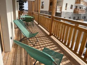 a porch with green chairs and tables on a deck at Midori T3 77 m2 in Vars