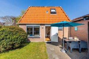 a house with an orange roof with a table and an umbrella at Daisy-Rose aan de Jan Tooropstraat in Domburg