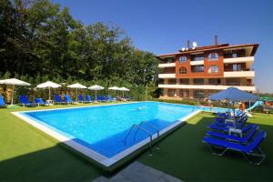 a swimming pool with chairs and umbrellas next to a building at Studio Wave 35 in Shkorpilovtsi