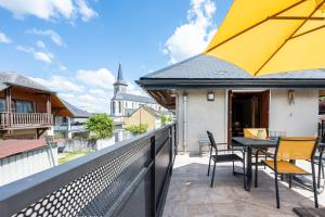 ein Balkon mit Tisch und Stühlen und einem gelben Sonnenschirm in der Unterkunft La Maison Marie Andre in Albens