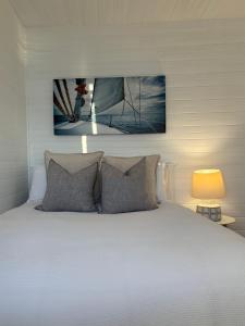 a bedroom with a white bed with a picture above it at Sydney Harbourfront Boathouse and Studio Escape in Sydney
