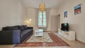 ein Wohnzimmer mit Sofa und Fernseher in der Unterkunft Grande Maison avec piscine, parking et wifi in Balaruc-les-Bains