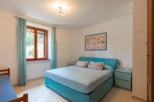 a bedroom with a blue bed and a window at Casa Alessia , il tuo angolo di pace a Nisporto in Nisporto