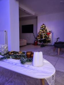 a christmas tree in a living room with a table at Basement Suite in Tríkala +3 photos