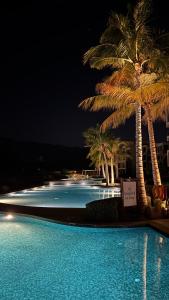 a large swimming pool with palm trees at night at منتجع جبل السيفه in Muscat