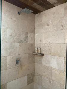 a bathroom with a shower with a stone wall at Tuwi Villa Ubud in Ubud +69 photos