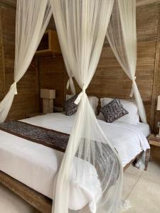 two beds with white drapes in a bedroom at Tuwi Villa Ubud in Ubud