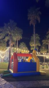 a slide on a beach with palm trees at night at منتجع جبل السيفه in Muscat