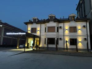 a large white building with a store on a street at Safia Guest House in Andijan