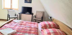 a bedroom with a bed and two chairs and a tv at Gästehaus zum Schlossberg in Vogtsburg