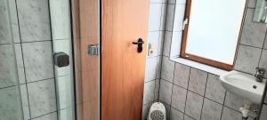a bathroom with a wooden door and a sink at Gästehaus zum Schlossberg in Vogtsburg