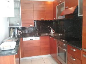 a kitchen with wooden cabinets and black counter tops at Luxury Apartment with Sea View! in Patra +4 photos