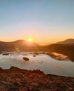 a sunrise over a body of water with the sun setting at Catbells Sunrise Cottage Borrowdale Lake District in Keswick