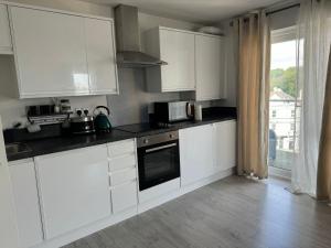 a white kitchen with white cabinets and a window at Bright & Stylish en-suite bedroom suitable for singles, couples, and families in a 2bed apartment in Chatham