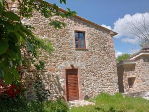 an old stone building with a door and a window at Podere Santa Benedetta camera in Ribolla