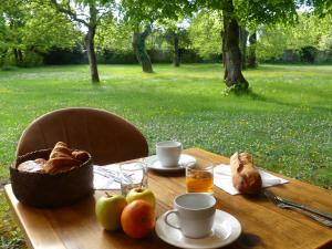 a table with bread and coffee and a basket of fruit at Hôtel et SPA du Château in Lagord
