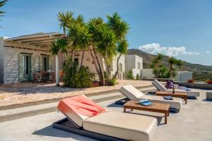 a patio with couches and tables and palm trees at MEGAS GIALOS HARMONY in Megas Gialos - Nites