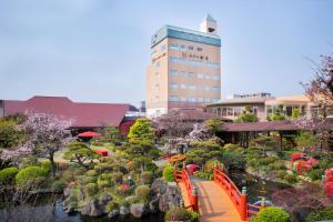a bridge over a garden with a building in the background at Hotel Marital Sousei Kurume in Kurume