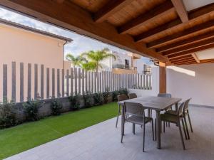 een patio met een tafel, stoelen en gras bij Rupes House in Roccella Ionica