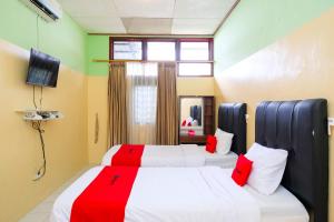 a bedroom with two beds with red and white sheets at RedDoorz Syariah at Omah Pathok Malioboro in Yogyakarta +34 photos