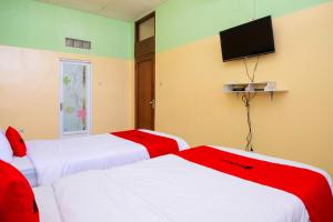 two beds in a room with a tv on the wall at RedDoorz Syariah at Omah Pathok Malioboro in Yogyakarta