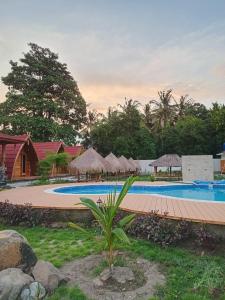 a resort with a swimming pool with umbrellas at Villa Aisyah sumbawa in Maluk