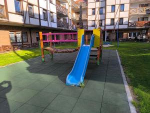 a playground in front of a building with a slide at Apartamenty Turkusowe in Rowy