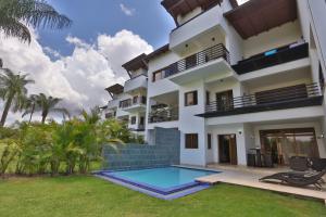 an exterior view of a building with a swimming pool at Sybaris Suites & Residences in Juan Dolio