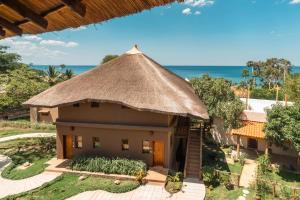 a house with a thatched roof with the ocean in the background at Micala Lodge in Lago
