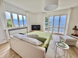 a bedroom with a bed and a couch and windows at Villa Miralago in Tronzano Lago Maggiore