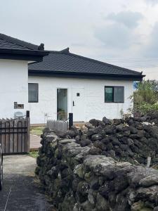 a stone fence in front of a house at Pakbyul Gimmori in Jeju