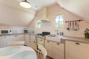 a kitchen with white cabinets and a sink and a table at Gite Cottage de la Douloustre in Montgaillard +12 photos