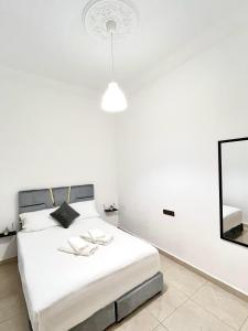Un dormitorio blanco con una cama y un espejo. en Sara Apartment Parking free, en Chefchaouen