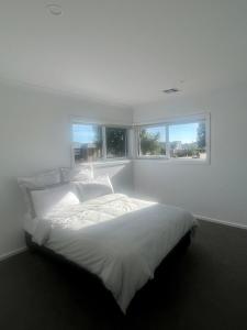 a white bedroom with a large bed with two windows at Yarrawonga Golf & Lake Getaway in Yarrawonga