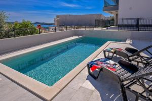 een zwembad met twee stoelen en een tafel bij Apartments 5 Stars Lux XYZ in Rogoznica