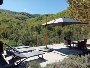 a group of chairs and an umbrella on a patio at Camerana La Casa Rossa in Camerana 