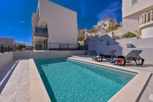 a swimming pool with two chairs next to a house at Apartments Penthouse lux XYZ in Rogoznica