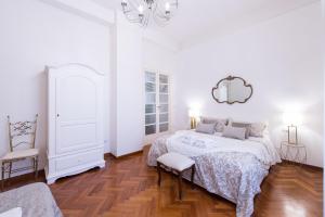 een witte slaapkamer met een bed en een spiegel bij Carità Grandi Residenze Napoli in Napels