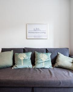a couch with pillows and a picture on the wall at Kensington Prime Apartments in London