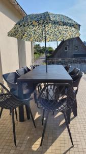 a table with chairs and an umbrella on a patio at Maison 4 Chb prox Mer, Golfs, Marais Salants, Balades in Guérande