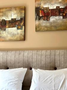 two paintings hanging above a bed with white pillows at Tinos Boutique House in Tinos