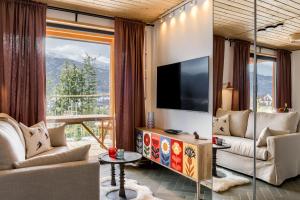 a living room with a large window and a television at TatryTop Domy Manowce z jacuzzi in Kościelisko