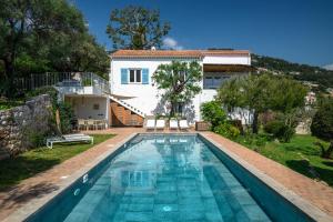 a villa with a swimming pool in front of a house at Villa Shangrila, charming house with sea view, swimming pool and garden nr Monaco and Italy in Roquebrune-Cap-Martin