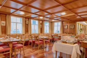 a dining room with tables and chairs and windows at Hotel Hecht in Appenzell