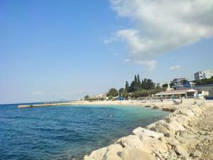 a beach with rocks and the ocean on a sunny day at Zara apartma in Podstrana