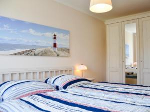 a bedroom with a bed with a lighthouse painting on the wall at Haus am Deich in Utersum