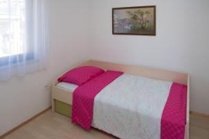 a small bedroom with a bed with a pink blanket at Zara apartma in Podstrana