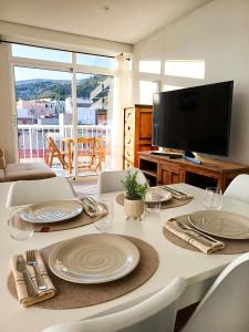 mesa de comedor con platos blancos y TV en GLP Postiguet 2, en Alicante