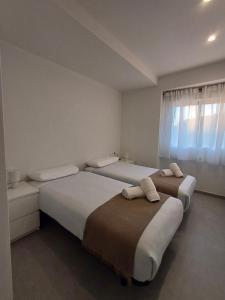 Dos camas en una habitación blanca con ventana. en GLP Postiguet 2, en Alicante 14 fotos más